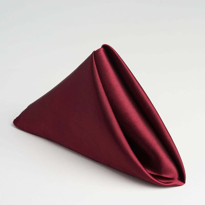 Burgundy satin napkin elegantly folded in a triangular shape