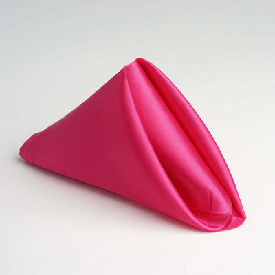 Pink fabric napkin folded in a cone shape on a white background.
