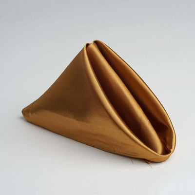 Gold satin napkin folded elegantly in a triangular shape.
