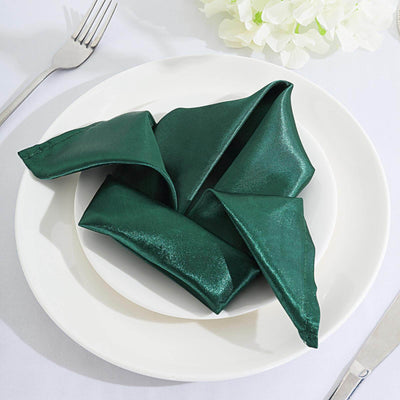 Elegant dark green napkin folded creatively on a white plate.