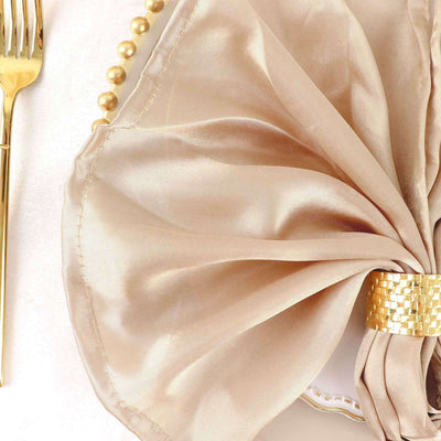 Elegant gold satin napkin with a decorative ring on a plate.