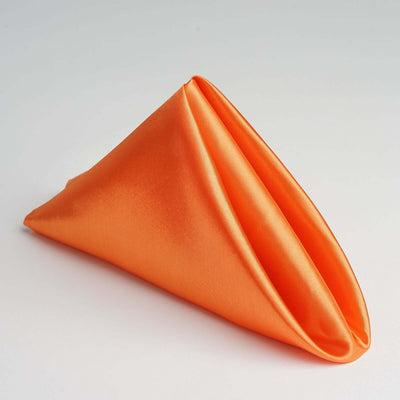 Orange satin napkin folded in a triangular shape.