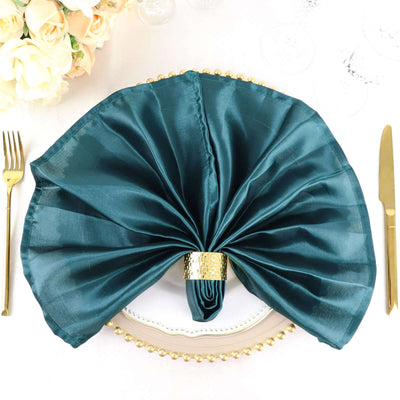 Elegant teal satin napkin with gold ring on a decorated dinner plate.