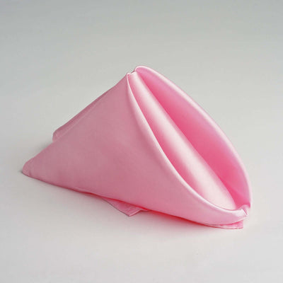 Pink silk napkin folded elegantly in a cone shape.
