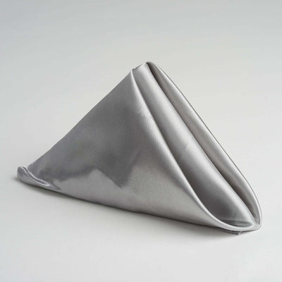 Silver satin napkin folded elegantly in a triangular shape.