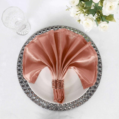 Elegant blush satin napkin arranged in a fan shape on a decorative plate.