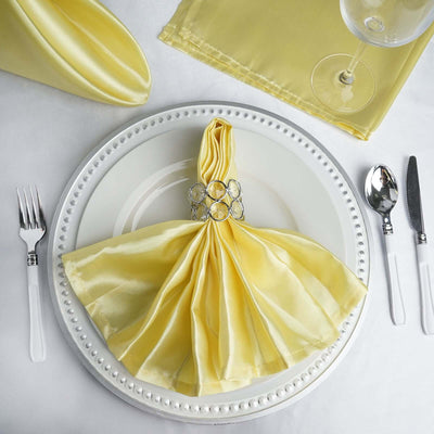 Elegant yellow satin napkin with jeweled ring on a decorative plate setting.
