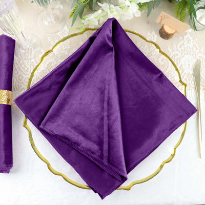 Purple velvet napkin elegantly folded on a decorative gold plate.