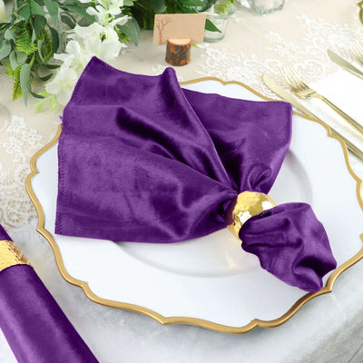 Purple napkin elegantly draped on a white plate with a gold napkin ring.
