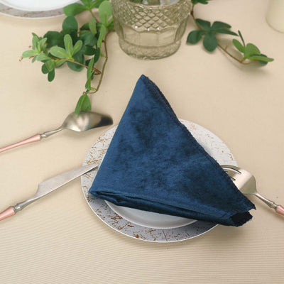 Navy blue velvet napkin on a decorative plate with cutlery.