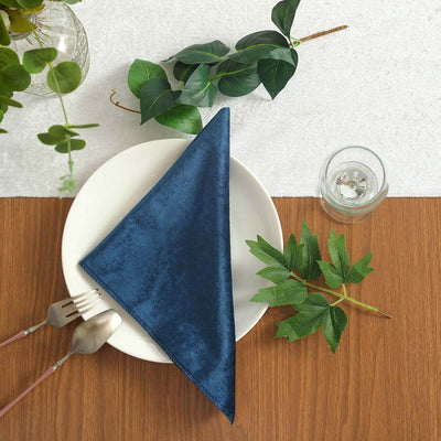 Navy blue napkin elegantly draped on a white plate with greenery and cutlery
