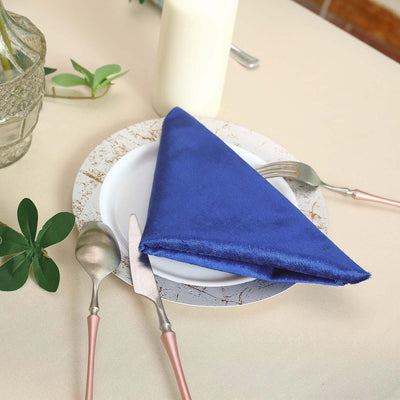 Blue satin napkin elegantly folded on a decorative plate with cutlery.