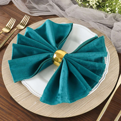Teal velvet napkin with gold ring on a decorative plate