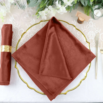 Burgundy velvet napkin elegantly arranged on a decorative gold plate.