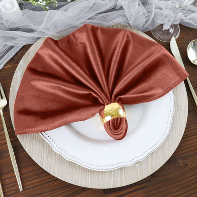 Elegant rust-colored napkin with gold ring on a textured plate setting.