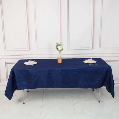 Navy blue tablecloth draped over a table set with plates and a flower vase.