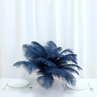 Navy blue feather centerpiece on a dining table with white plates and cutlery.