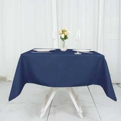 Navy tablecloth set on a table with a vase and wine glasses.