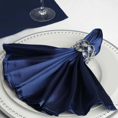 Elegant navy satin napkin with jeweled ring on a decorative plate.