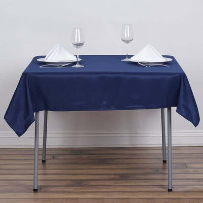 Navy blue tablecloth on a dining table set with plates and glasses.