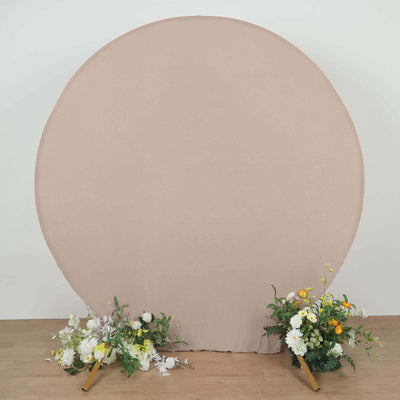 Round beige backdrop with floral arrangements on either side.