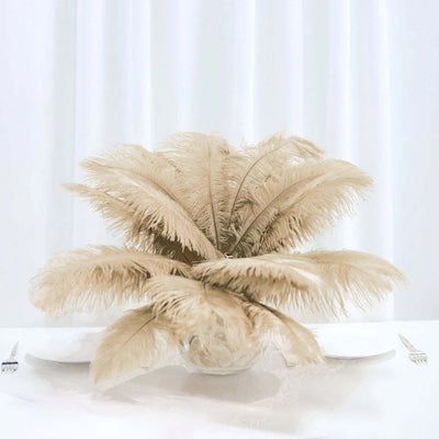 Beige feather centerpiece in a glass vase on a table.