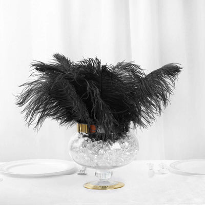 Black feather arrangement in a glass vase with ice crystals.