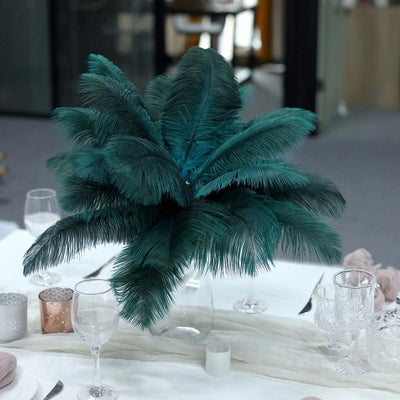 Teal feather centerpiece in a glass vase on a table setting.