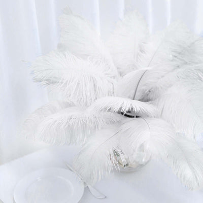 White feather arrangement in a glass vase against a plain backdrop
