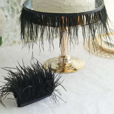 Black feather cake skirt and matching decoration on a table setting.