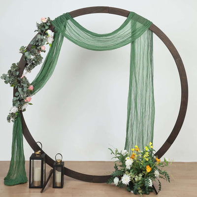 Decorative round arch with green drapery and floral accents, featuring lanterns and plants.