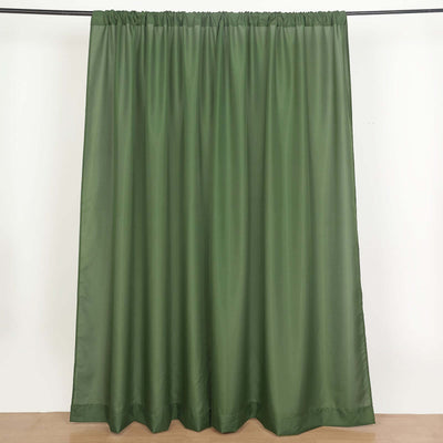 Green curtain panel hanging on a rod against a plain backdrop.
