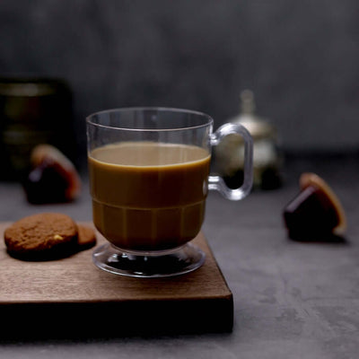 Clear glass coffee cup with cookies on a wooden board.