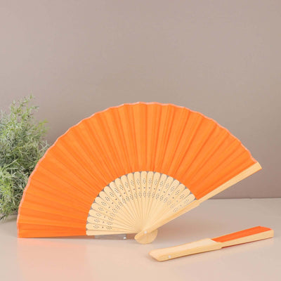 Orange folding fan with wooden handle on a neutral background.