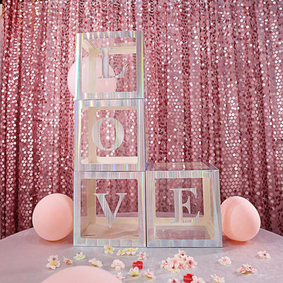 Decorative love blocks stacked with pink balloons and sequined backdrop.