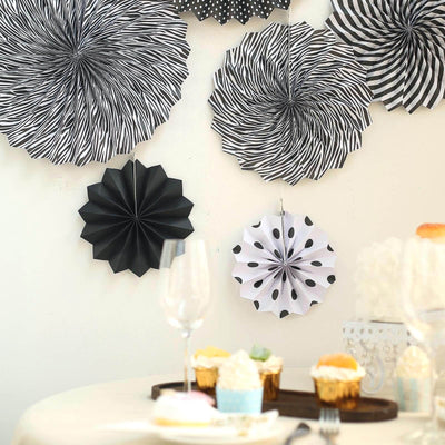 Black and white decorative paper fans hanging on a wall.