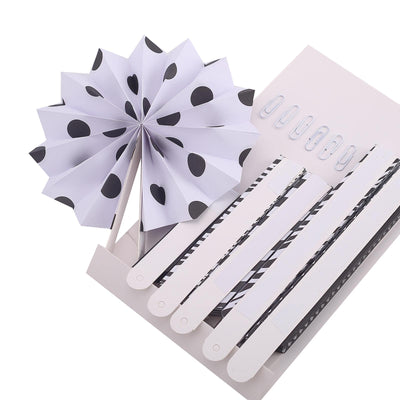 Black and white decorative paper fan and clips on a light background.