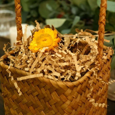Woven basket with yellow flower and shredded paper filler.