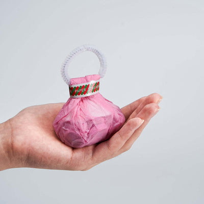 Pink paper-wrapped gift in a hand with a decorative ribbon