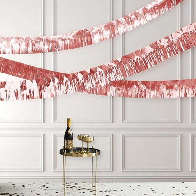 Rose gold party decorations with champagne and glasses on a stylish table.
