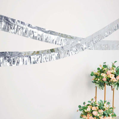 Silver fringed garland hanging above floral arrangements for decoration.