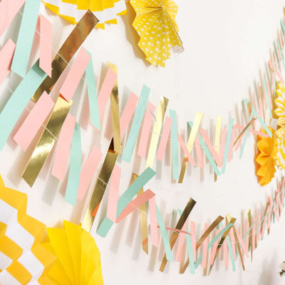 Colorful paper garland with gold accents and decorative fans hanging on a wall.