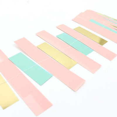 Colorful paper strips in pink, green, and gold arranged in a line.