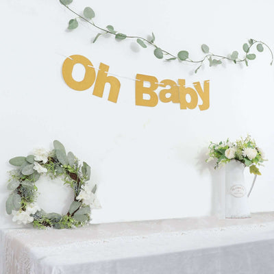 "Oh Baby" banner with greenery and floral accents on a table.
