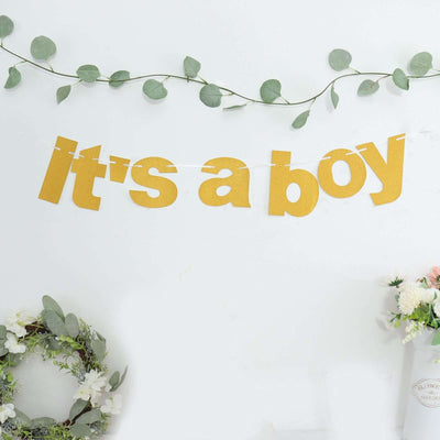 Gold "It's a boy" banner with greenery and floral decor