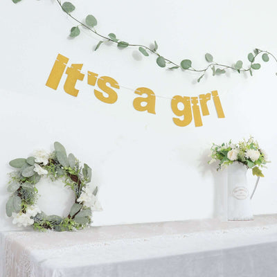 "It's a girl" banner decor with greenery and floral arrangements.