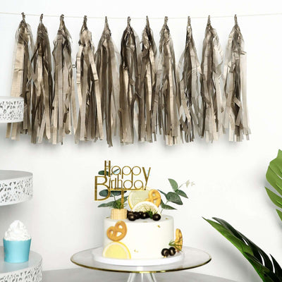 Birthday cake with gold "Happy Birthday" topper and decorative tassels.