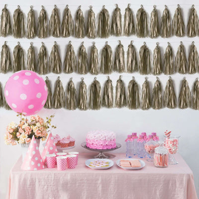 Birthday party decorations with tassel garland, cake, and festive tableware.