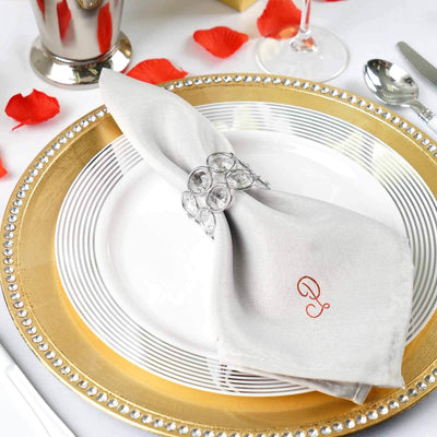 Elegant table setting with a silver napkin, crystal napkin ring, and gold charger plate.