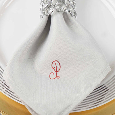 Gray napkin with red embroidered letter "P" elegantly displayed on a plate.